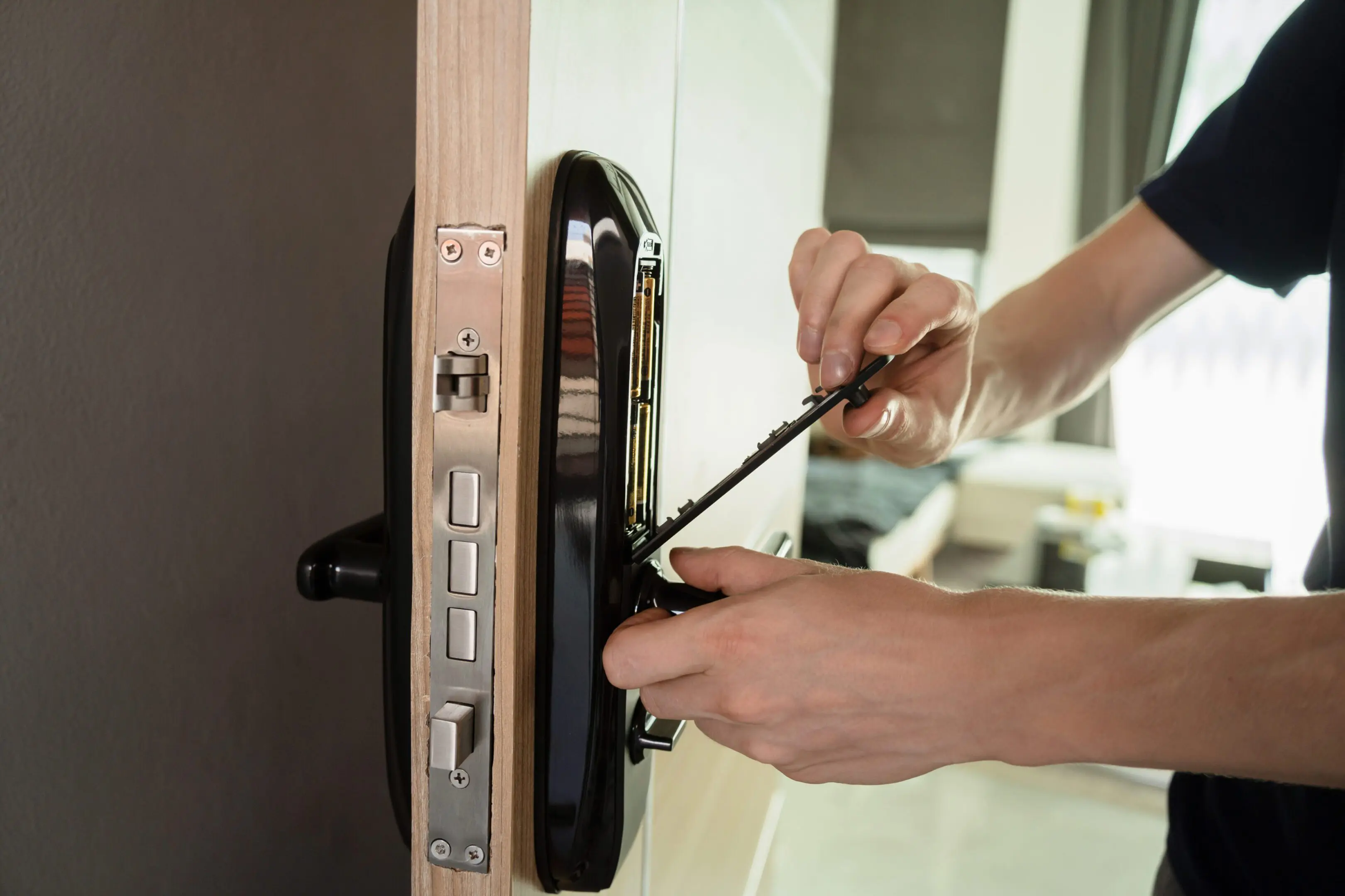 Person installing or repairing a digital door lock with a screwdriver.