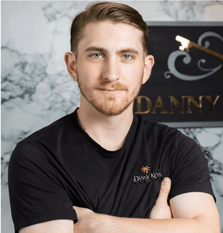 Young man with arms crossed in black shirt posing confidently.