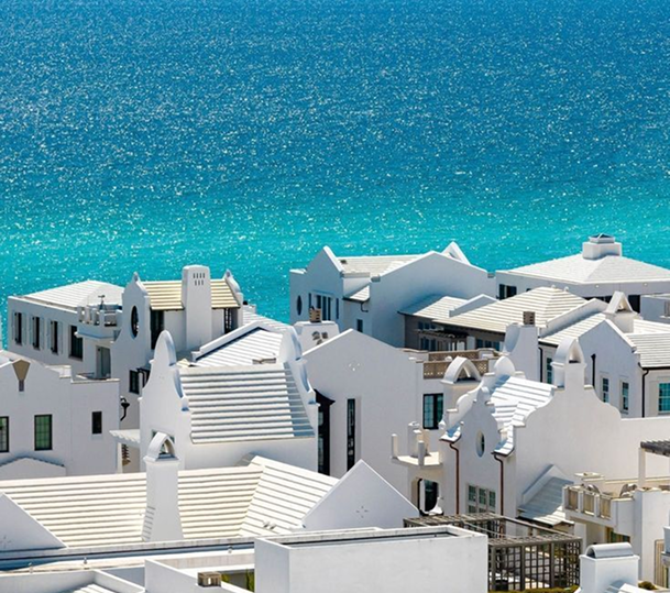 White rooftop houses against a turquoise sea under a clear sky.