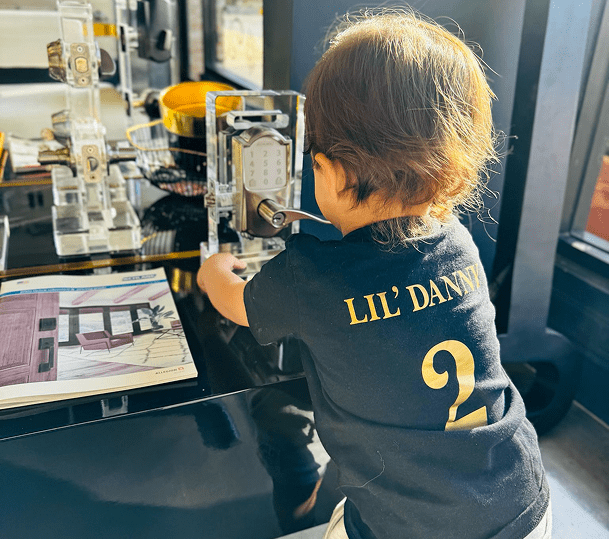 A child wearing a Lakers jersey makes coffee with an espresso machine.